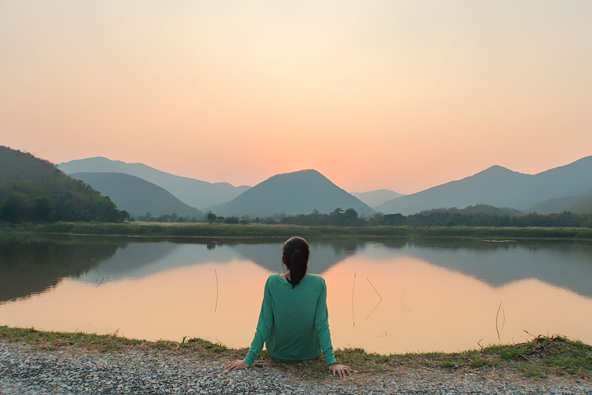 Woman facing lake at sunrise